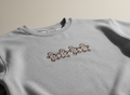 Gray sweatshirt with embroidered gingerbread men design on a beige background
